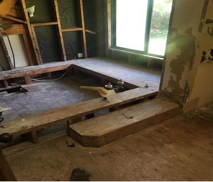 Master Bathroom tub that has been removed and all surrounding walls and flooring has been removed, exposing  wood foundation.