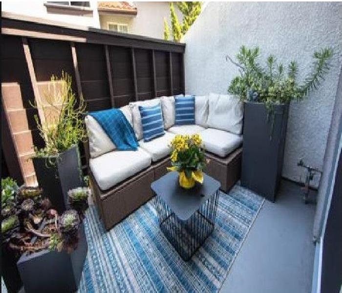 Townhome patio that has a striped blue patio couch with a center table. Bright colors