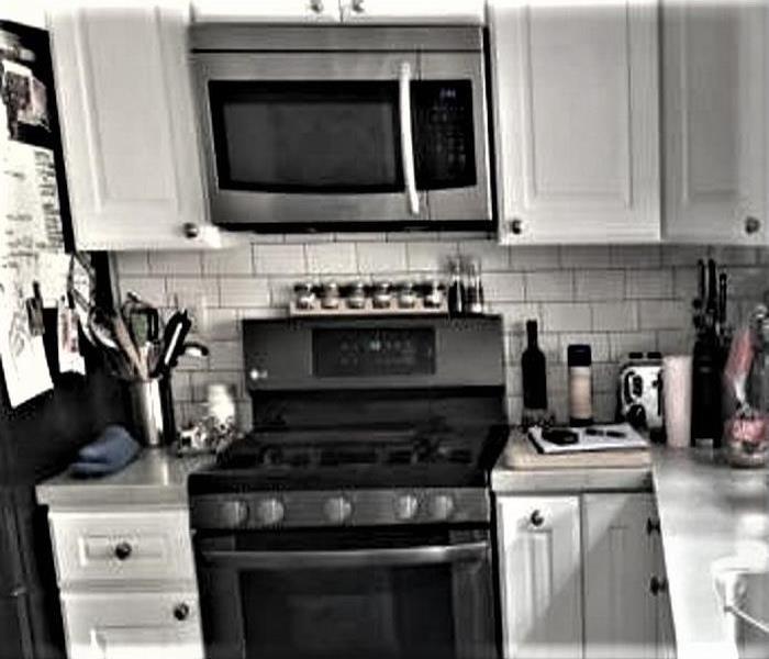 Kitchen area with a stove and microwave above.White cabinets in tact. 