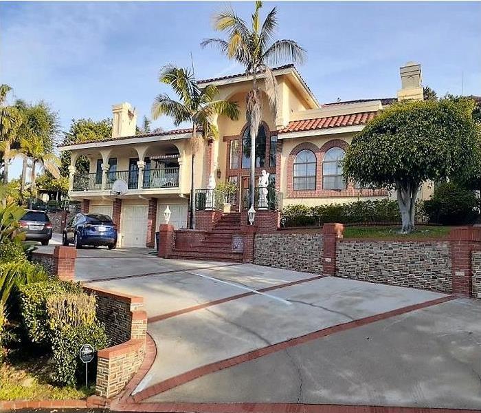 Multi million dollar mansion with a long driveway with 2 vehicles parked in the front.