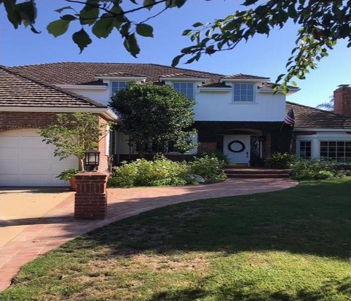 2 story home with wide panel windows with a red brick driveway.