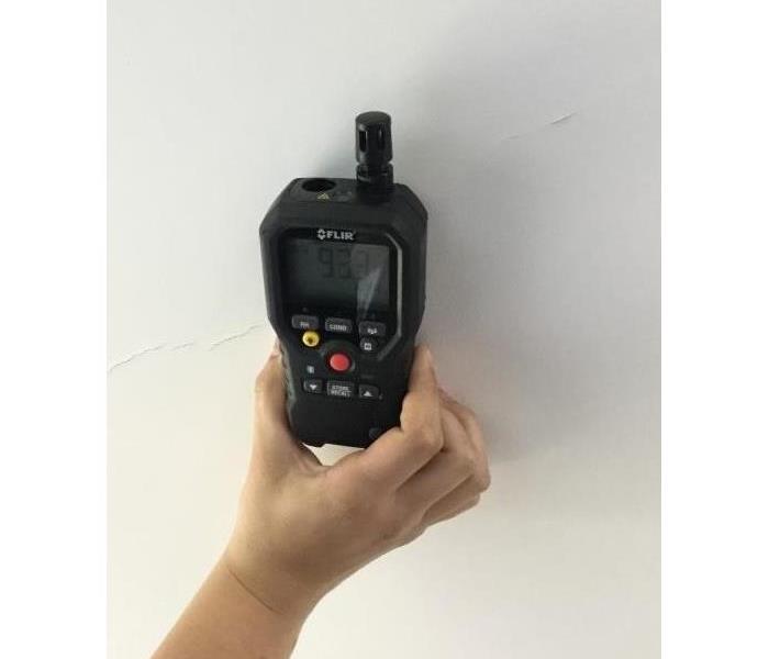 A handheld device with a digital monitor that is put against the affected wall, floor, or ceiling for moisture readings.