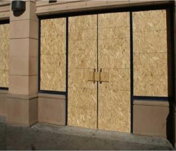 Front store door and window that boarded up with plywood. 
